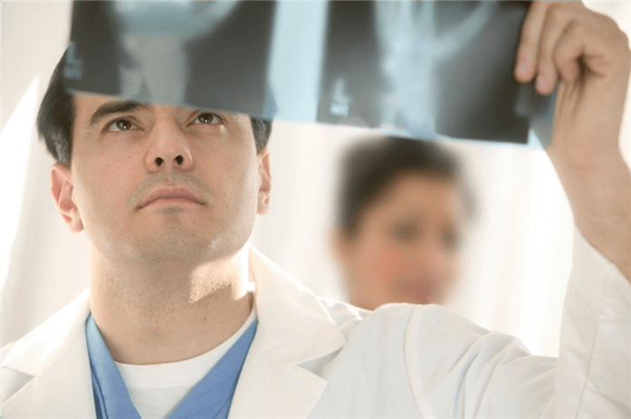 medicul examinează o imagine a articulației șoldului cu artroză